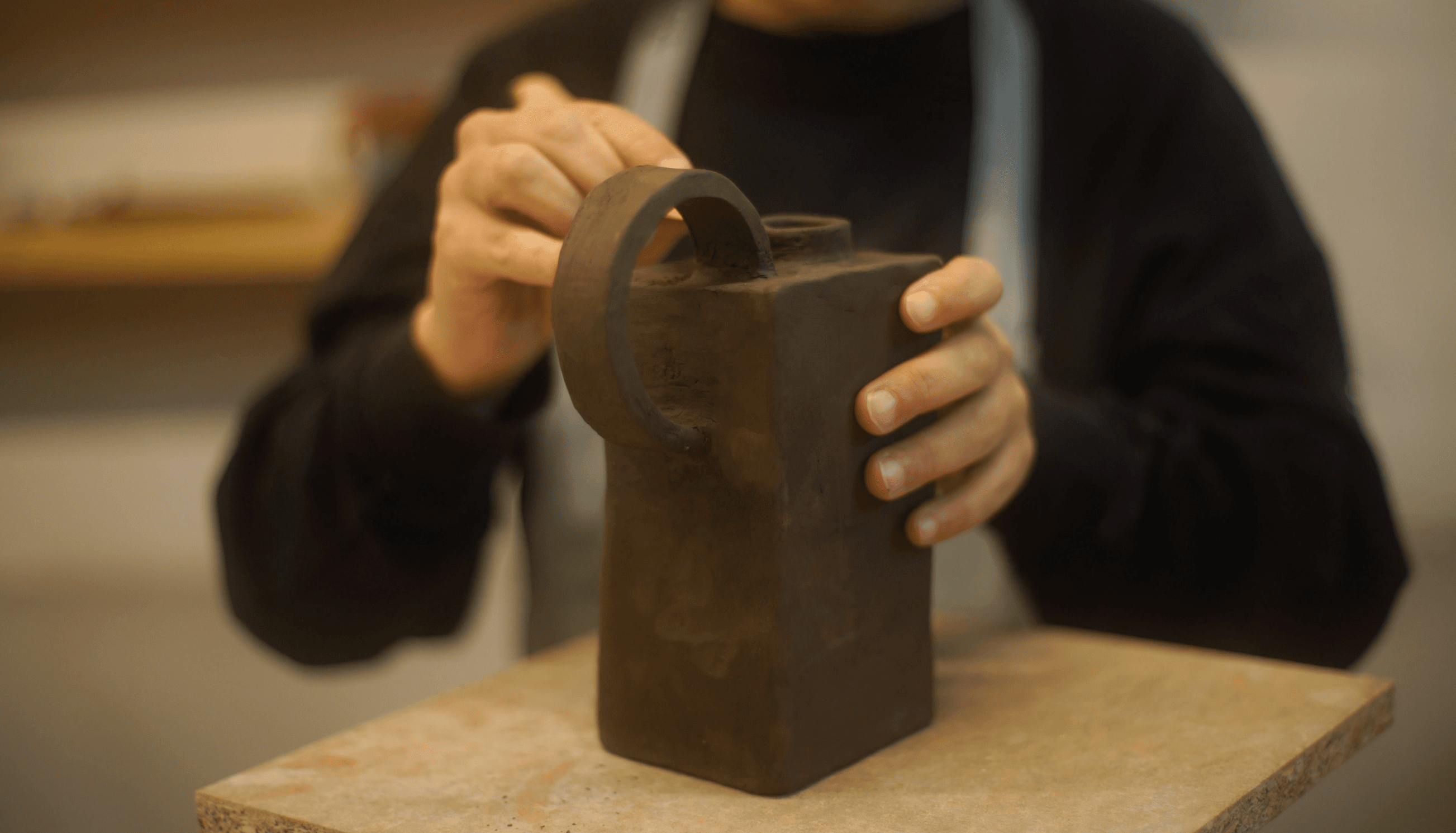 una persona modelando arcilla en la mesa de trabajo